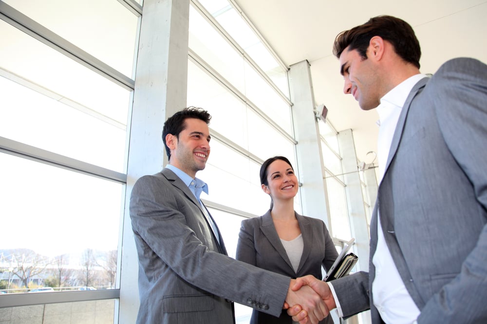 Business partners shaking hands in meeting hall-1
