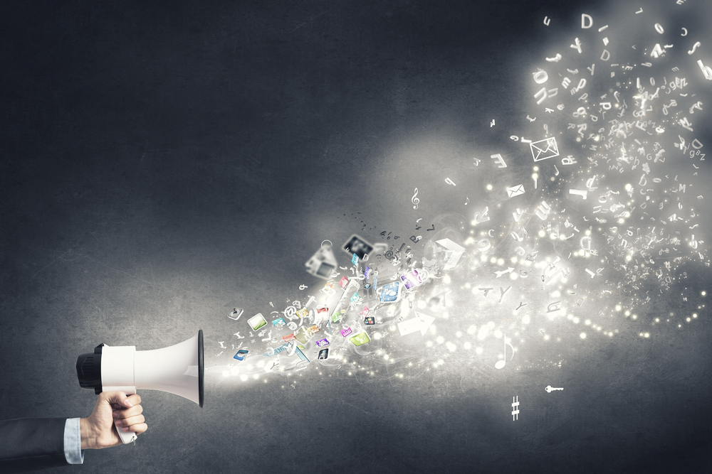 Businessman hand with loudspeaker and icons flying out